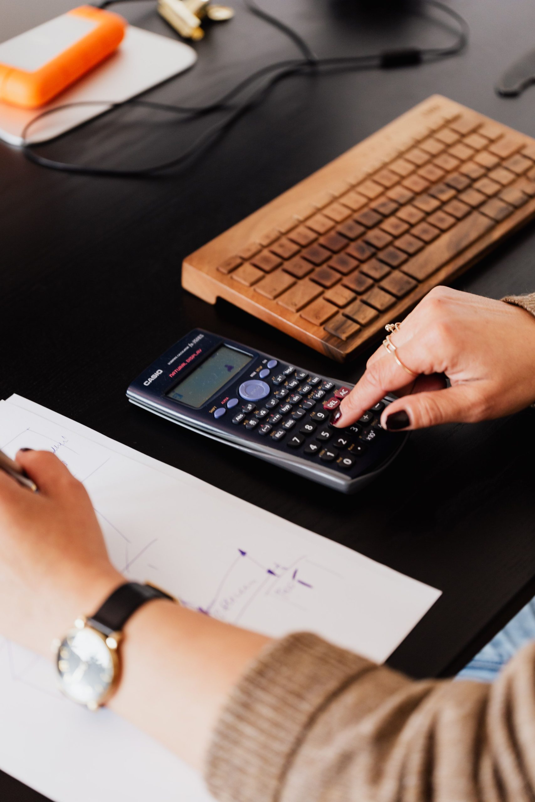 Bookkeeper checking cash figures with a calculator and notebook